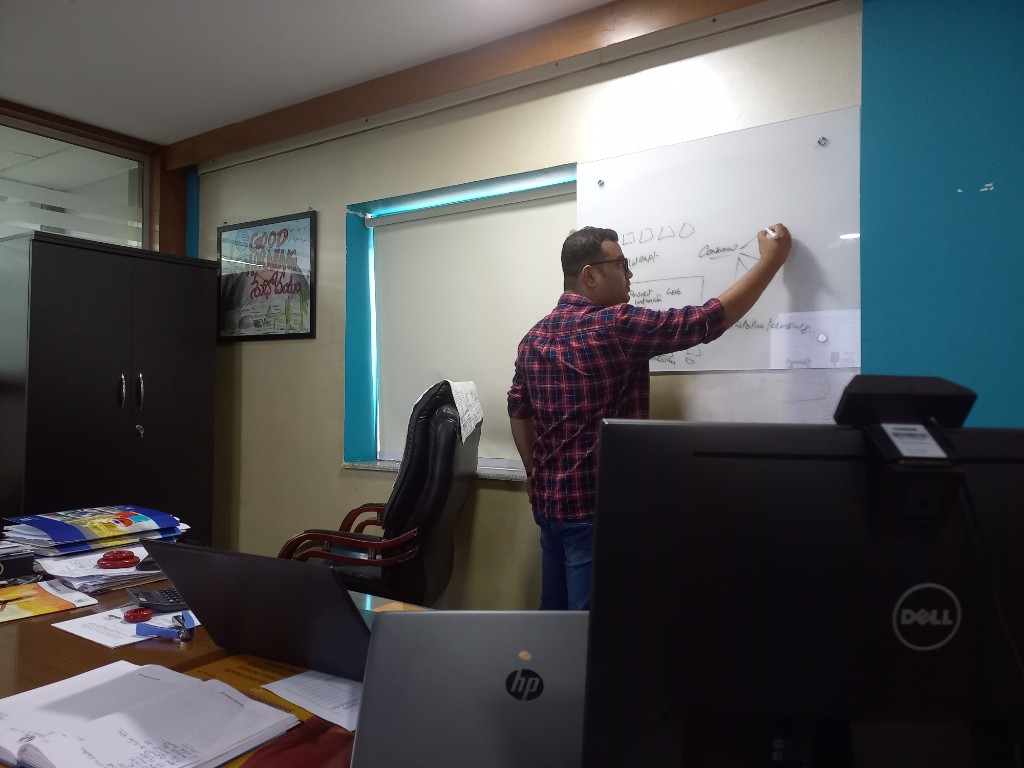 Naffys Mir at a whiteboard planning diagrams and workflows in the office.