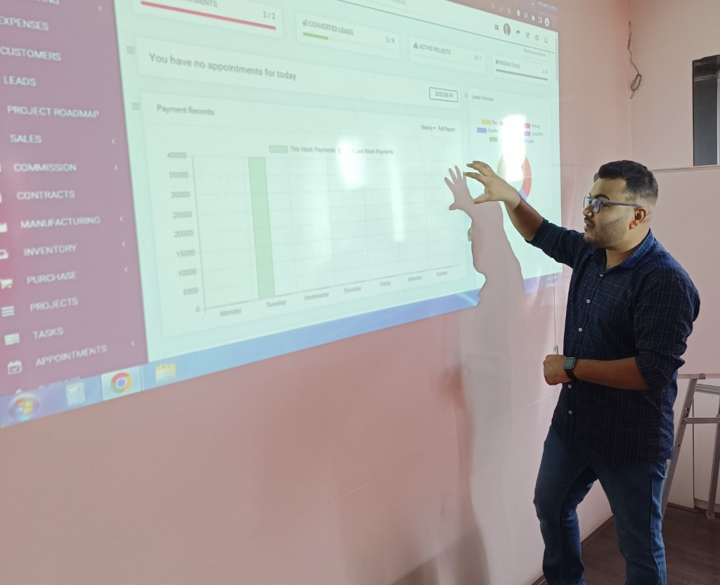 Naffys Mir presenting a business software dashboard projected on the wall.