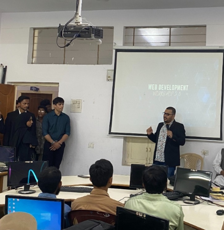 Naffys Mir leading a web development workshop in front of a projection screen.